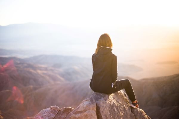 Woman sitting on rock peak facing away